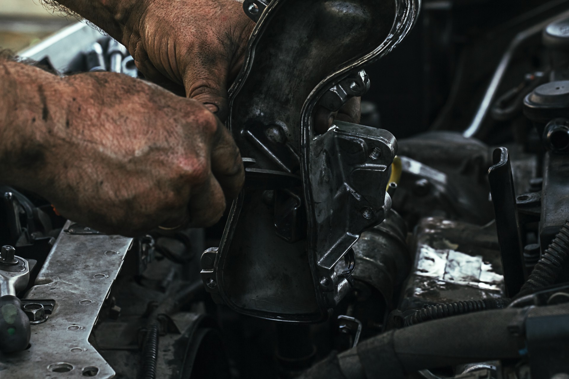 dirty, greasy hands of a man repairing the engine, EGR valve in the car close up