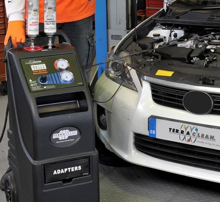 Car engine being serviced with TerraClean machine and technician in workshop.